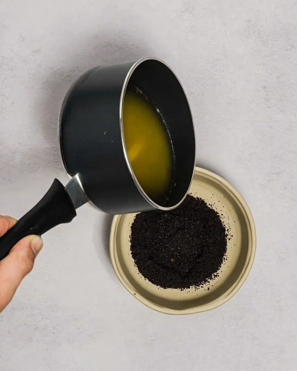 Pouring melted butter on to Oreo crumbs.