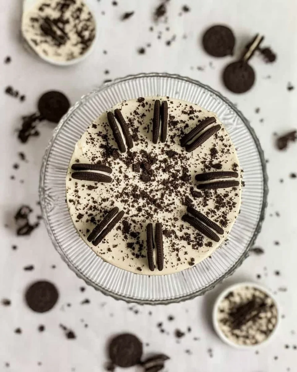 Oreo cheesecake on a cake stand and mini Oreo cheesecakes around it.