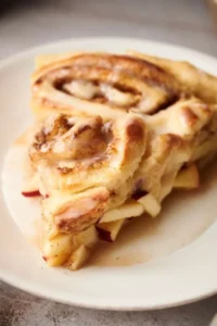 A slice of apple cinnamon roll on a plate.