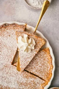 A cake slice holds a slice of freshly made cinnamon pie over the rest of the pie.