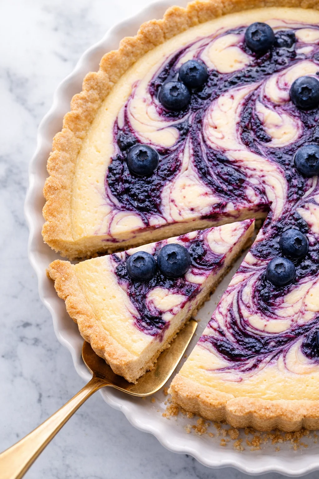 Close-up of a blueberry-swirl cheesecake with a golden crust and blueberries.