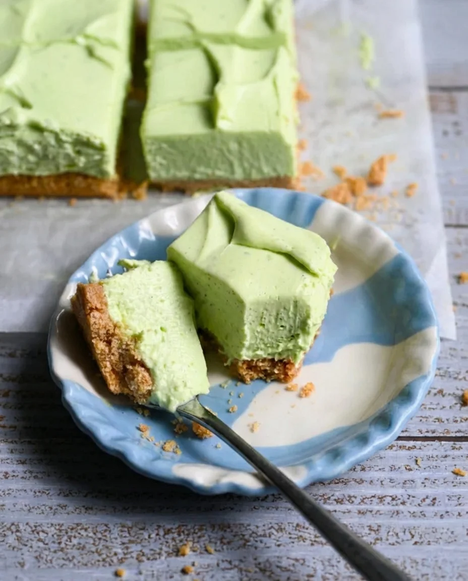 mint-green cheesecake slices with crumb crust on a blue and white plate