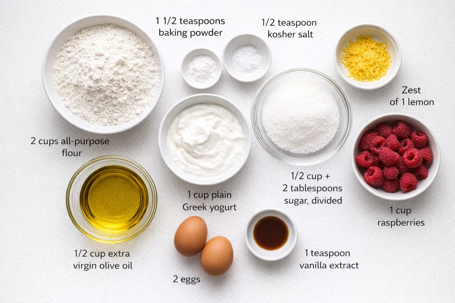 Measured ingredients arranged for Raspberry Lemon Muffins: 2 cups all-purpose flour, 1 1/2 teaspoons baking powder, 1/2 teaspoon kosher salt, 1 cup plain Greek yogurt, 1/2 cup extra virgin olive oil, 2 eggs