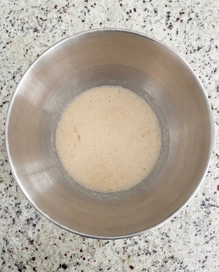 overhead view of a stainless steel mixing bowl with a mound of dry flour in the center