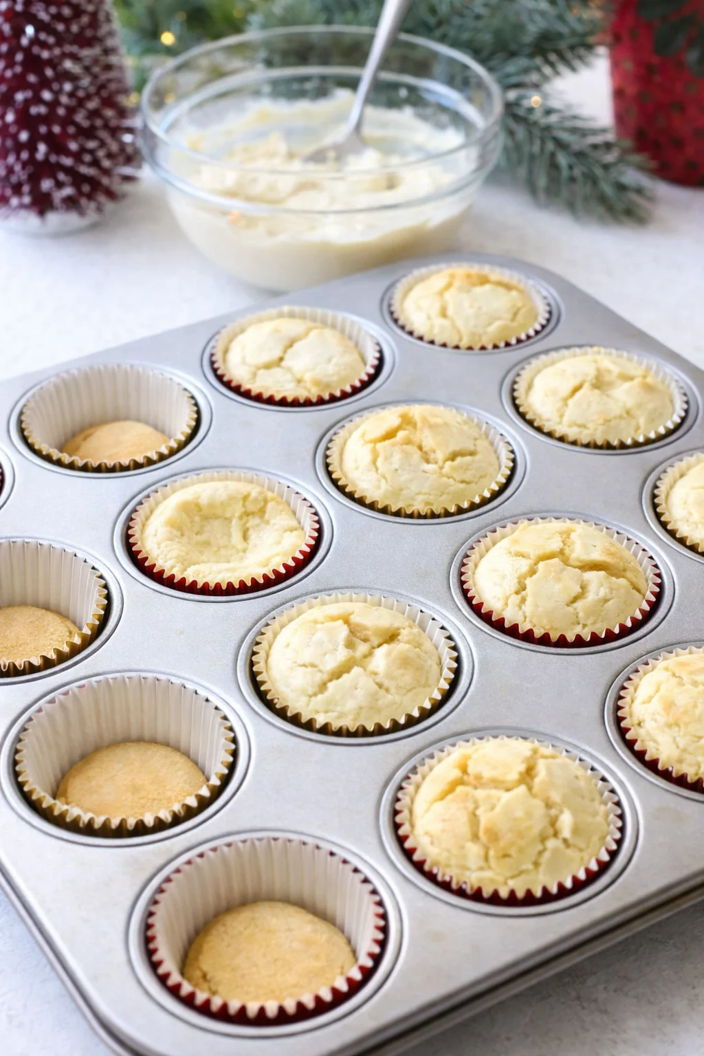 Cupcake liners filled with smooth batter over visible vanilla wafers, muffin pan being gently shaken.