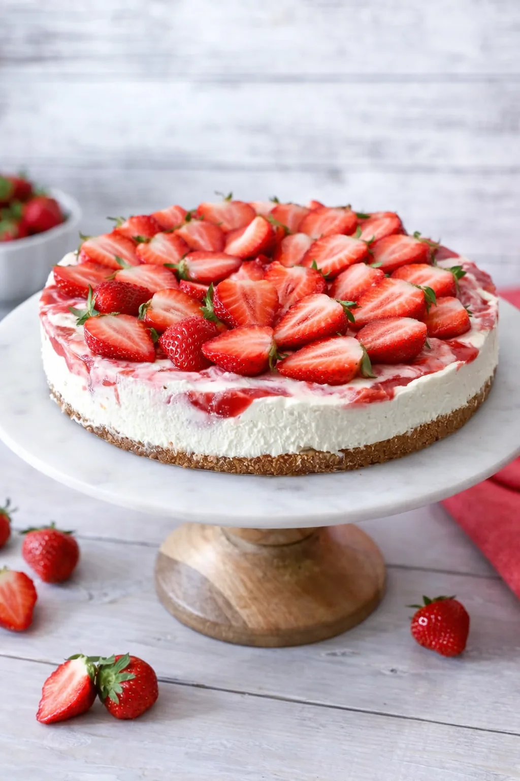 Springform sides removed, cheesecake on its base transferred to plate, topped with sliced strawberries
