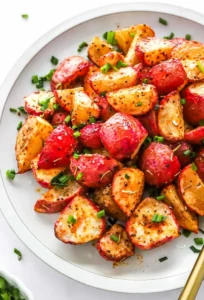 Plate filled with air fryer radishes topped with chopped chives with a gold spoon on the plate.