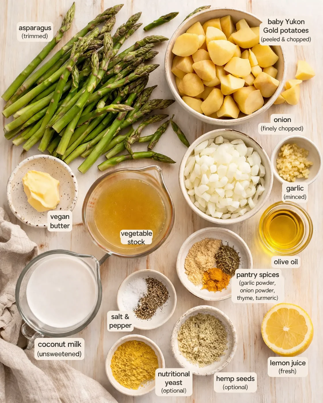 flat lay of asparagus, potatoes, onions, garlic, and bowls of stock, coconut milk, lemon, and spices.