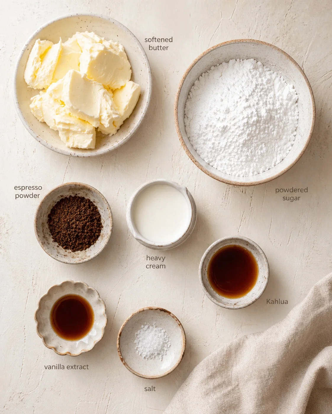 top-down view of baking ingredients in ceramic bowls: butter, powdered sugar, espresso powder, heavy cream, vanilla extract, salt, and kahlua