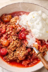 close-up of berry crumble with vanilla ice cream in a rustic speckled bowl
