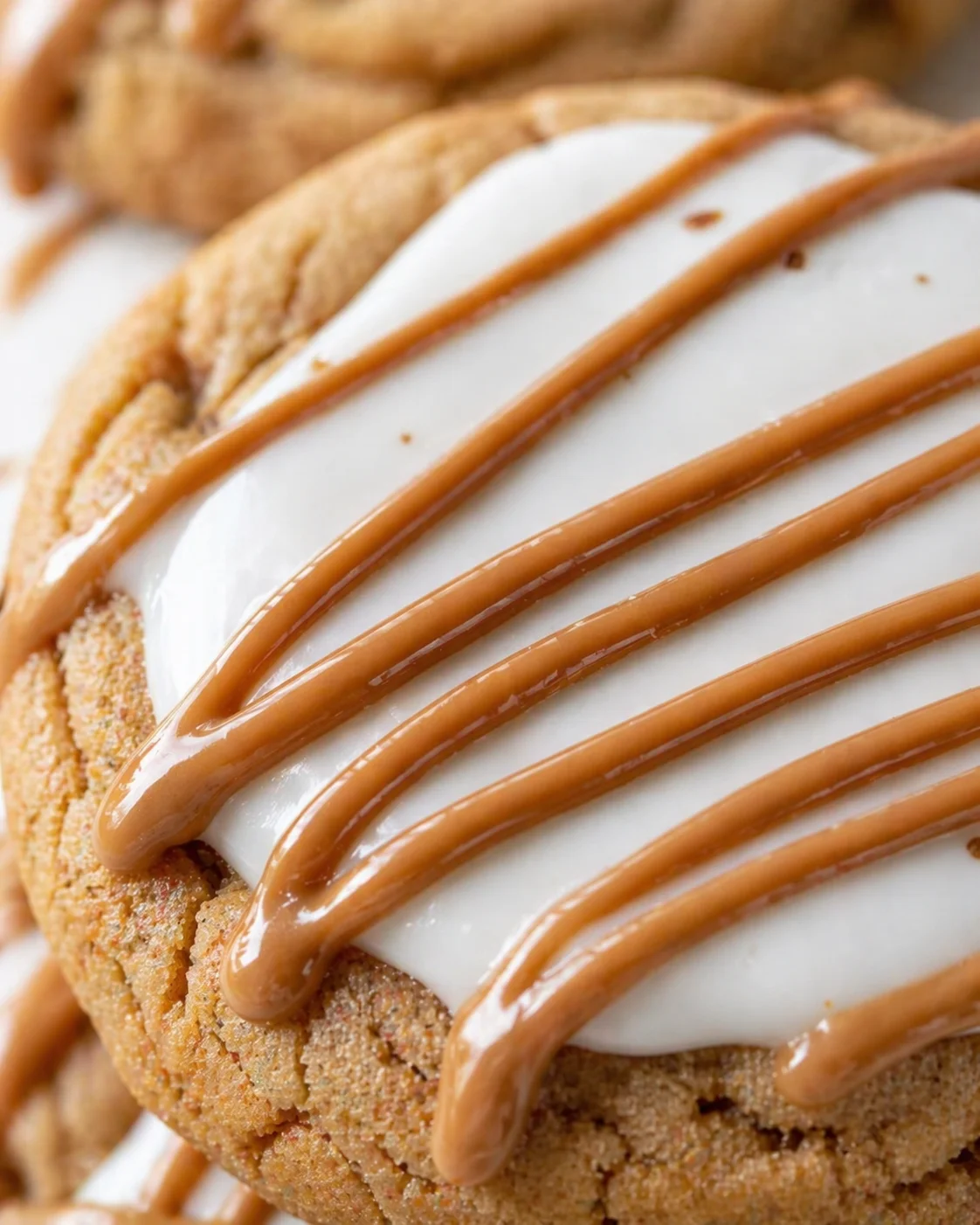 close-up of a golden cookie with white icing and caramel drizzle