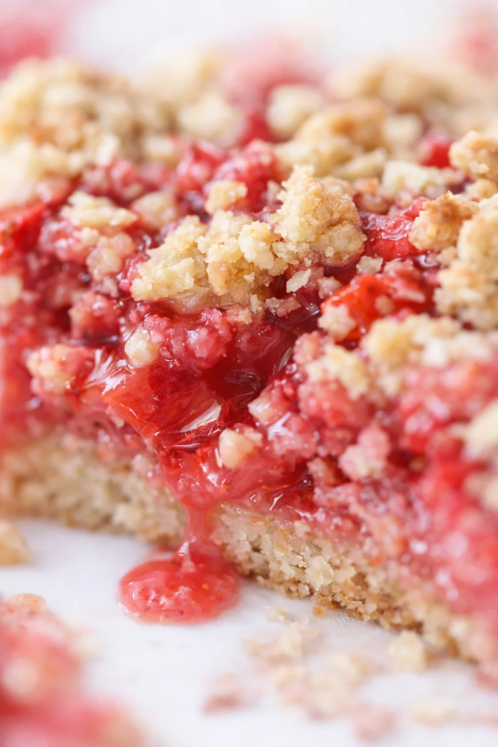 close-up of cherry crumble bar with gooey red filling and crumb topping