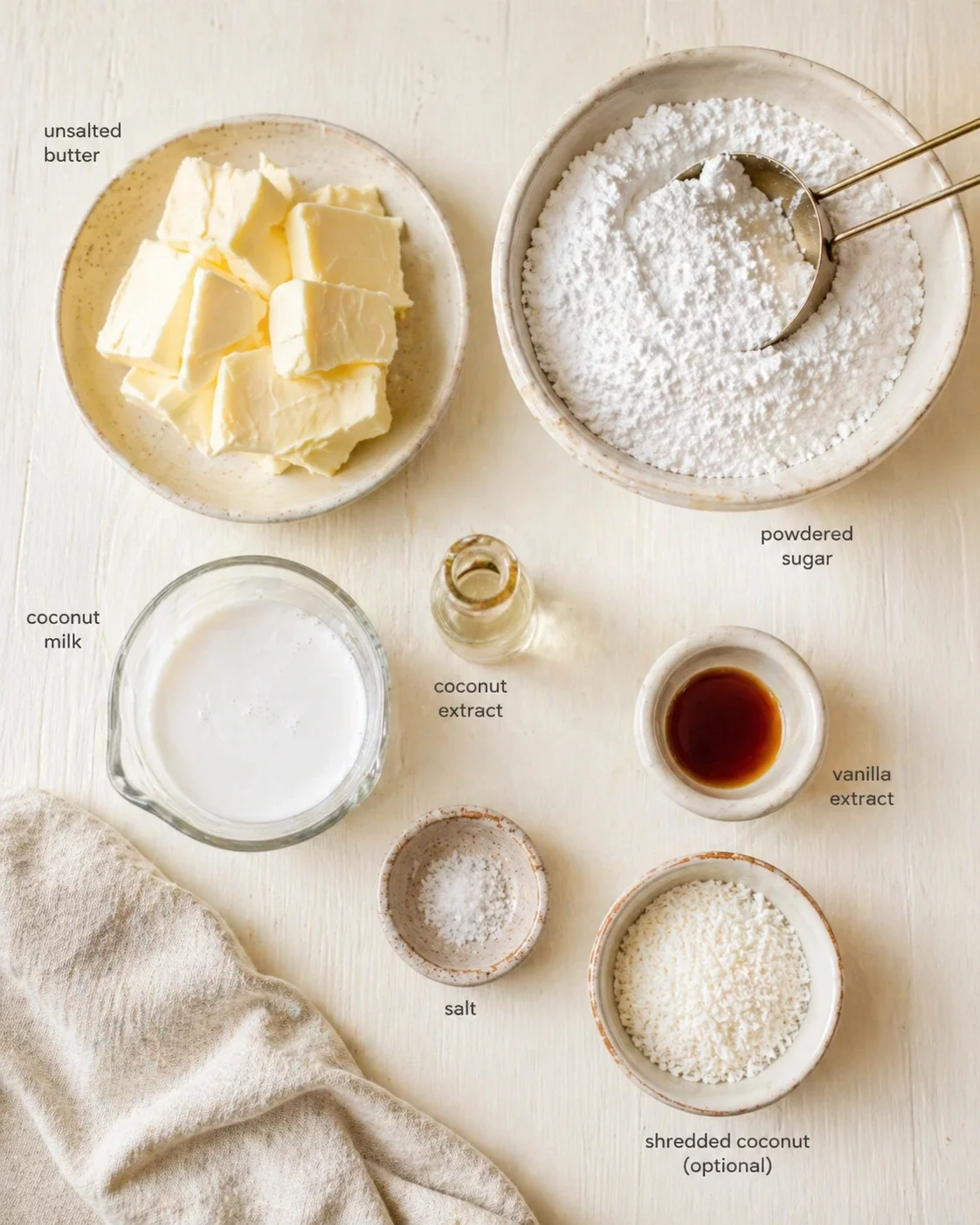 Top-down view of butter chunks, powdered sugar, coconut milk, extracts, salt, and shredded coconut.