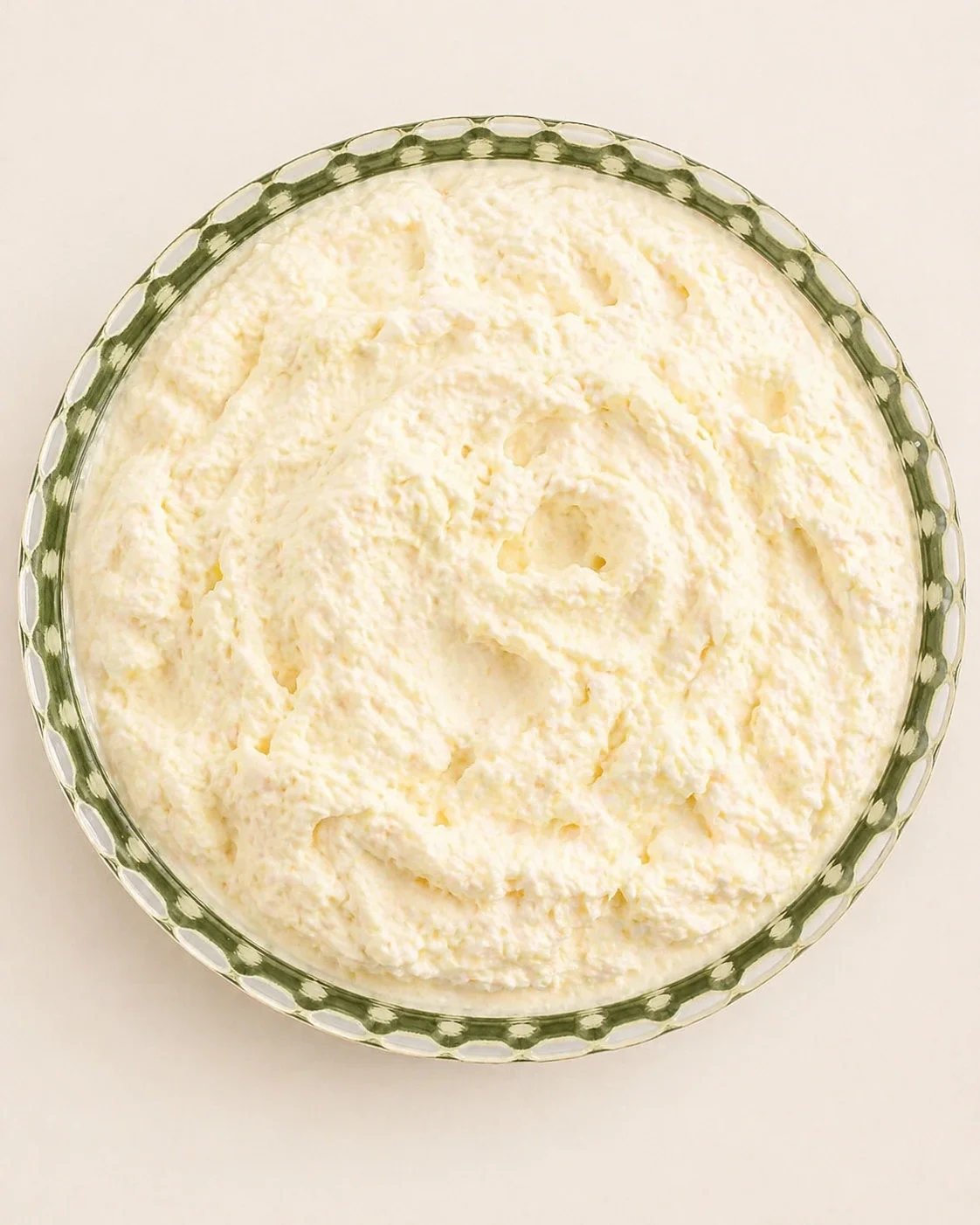 Overhead view of a green glass bowl filled with creamy mashed potatoes.
