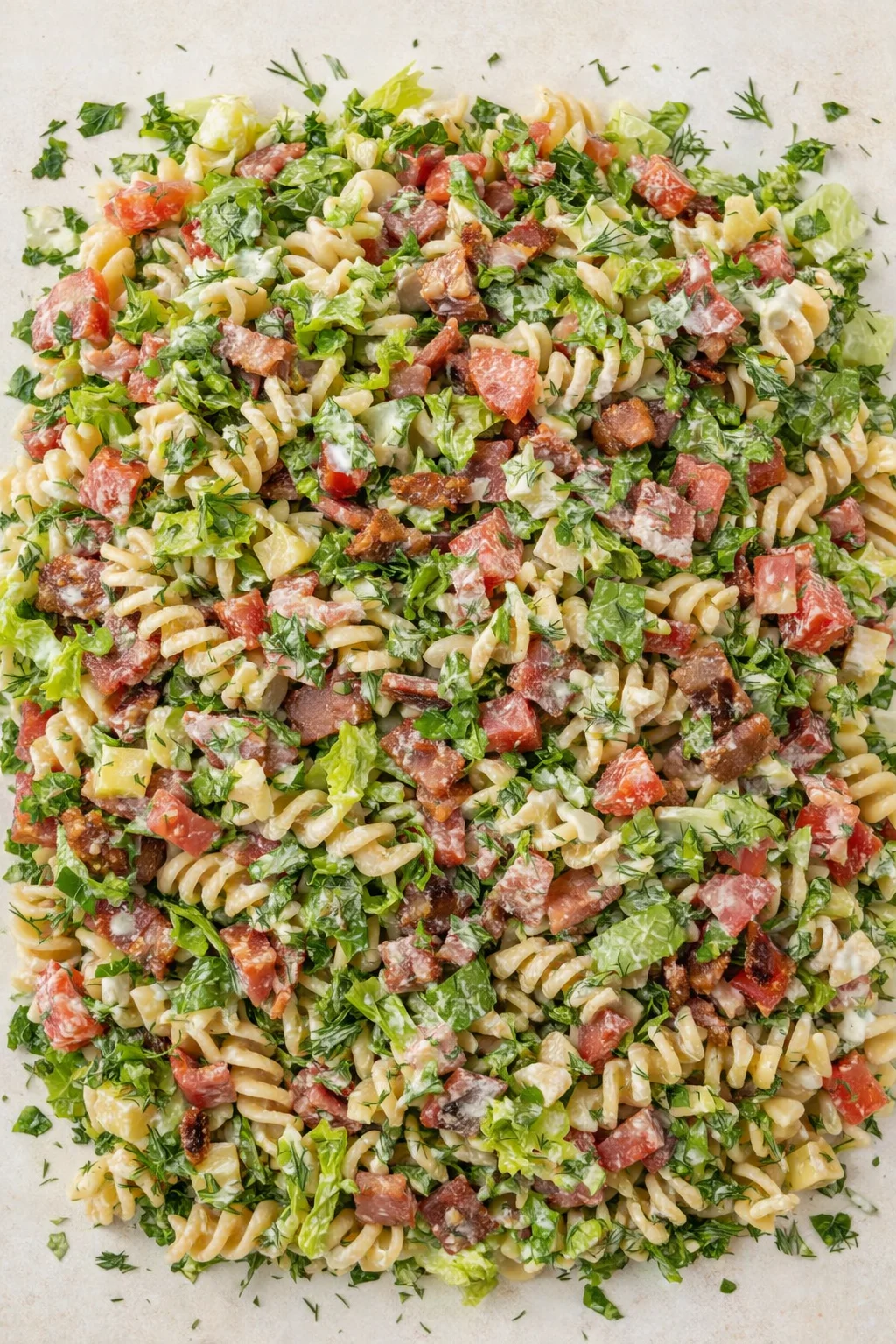 Overhead view of creamy pasta with bacon, tomatoes, and herbs on parchment