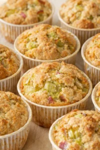 Close-up of crumble-topped savory muffins with celery chunks on a wooden surface