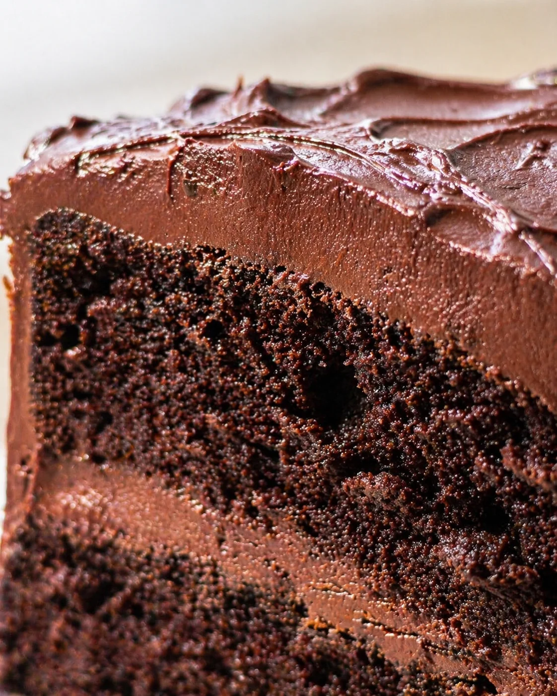 close-up of dense chocolate cake slice with glossy ganache on top, revealing moist crumb