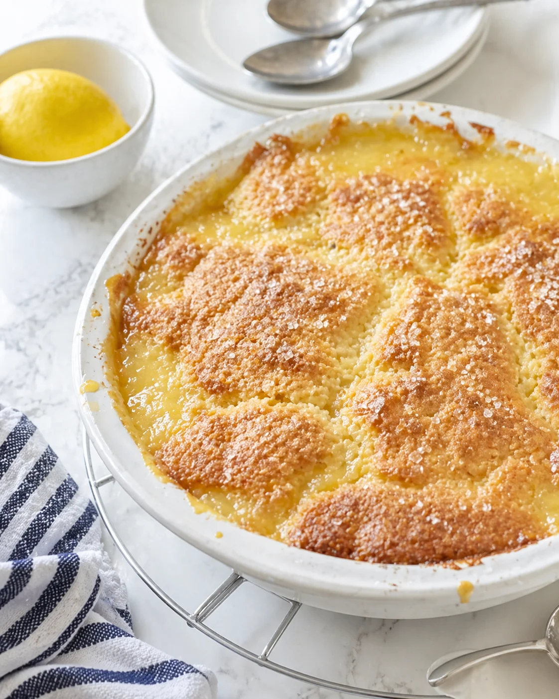 lemon bread pudding in a white dish with a golden crust and sugar topping