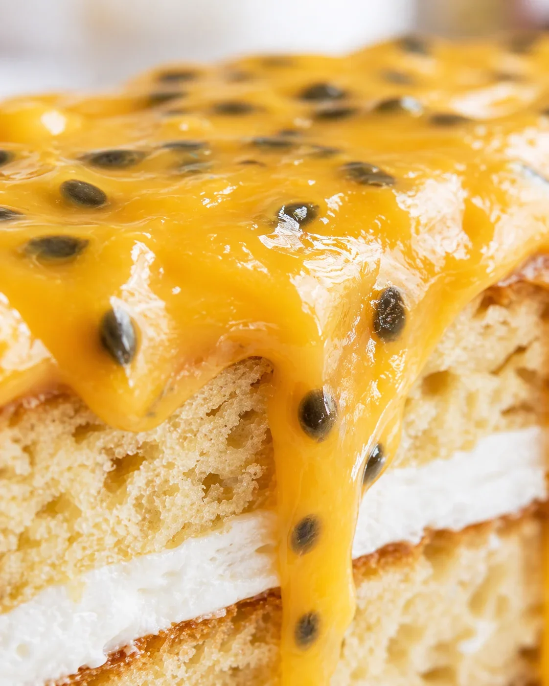Close-up of vibrant homemade passion fruit curd poured over cake layers.