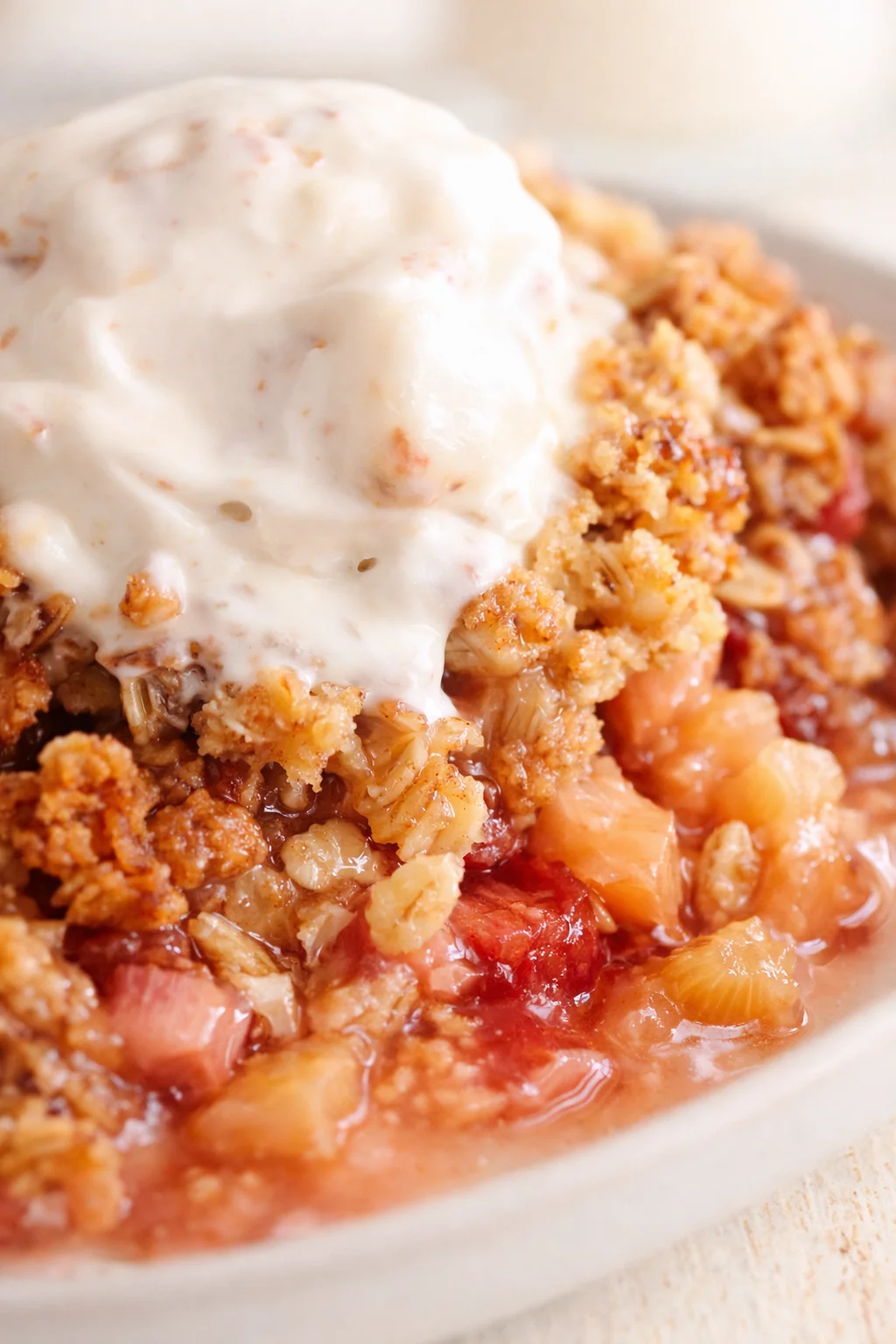 bowl of peach-berry crumble with a scoop of vanilla ice cream on top