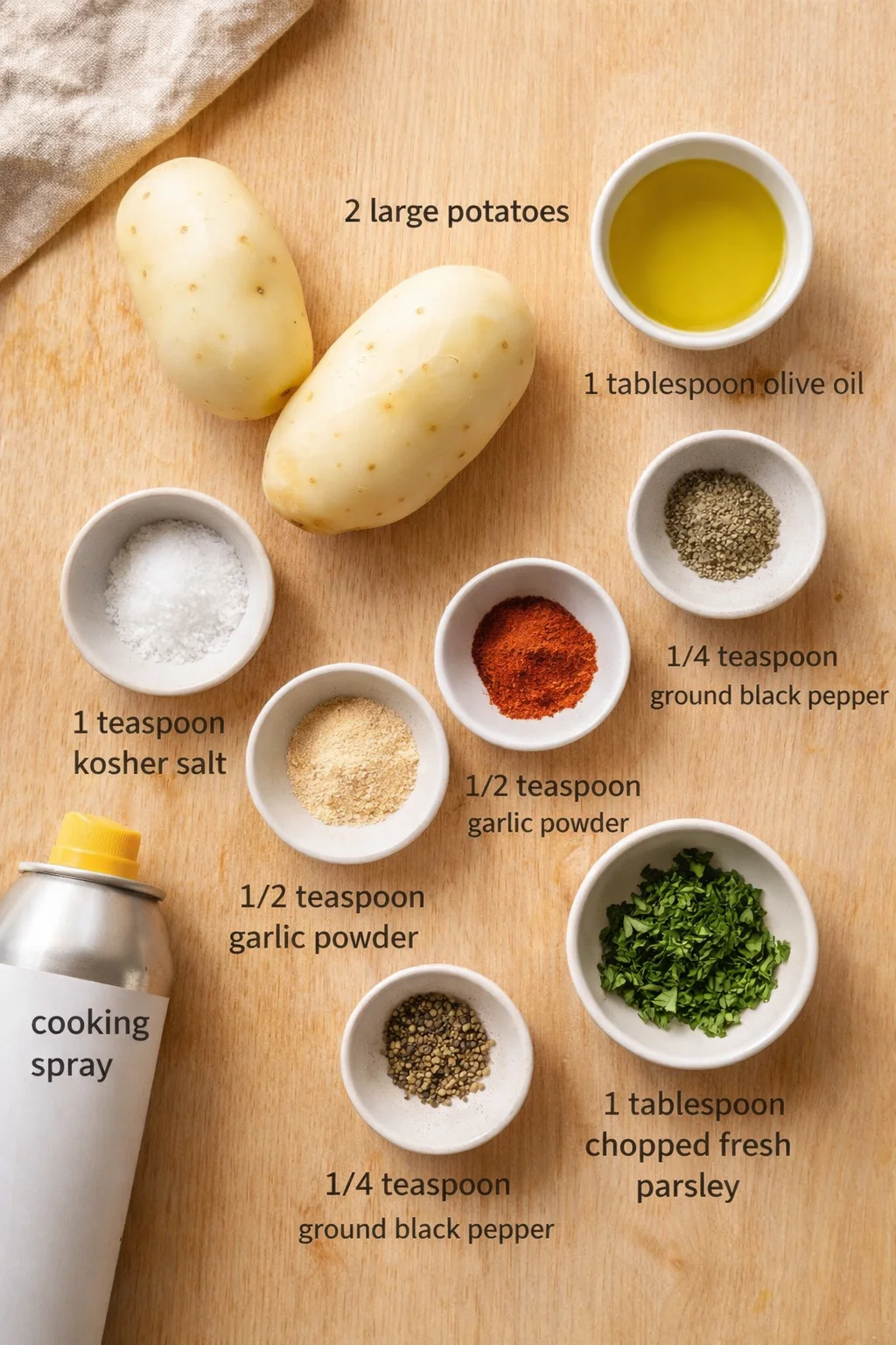 Two large potatoes surrounded by bowls of oil, salt, pepper, garlic powder, and parsley.