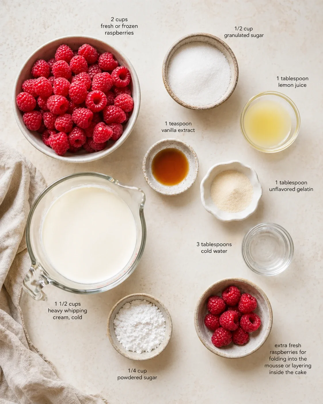 Overhead view of raspberries and baking ingredients with labeled quantities on a light countertop.