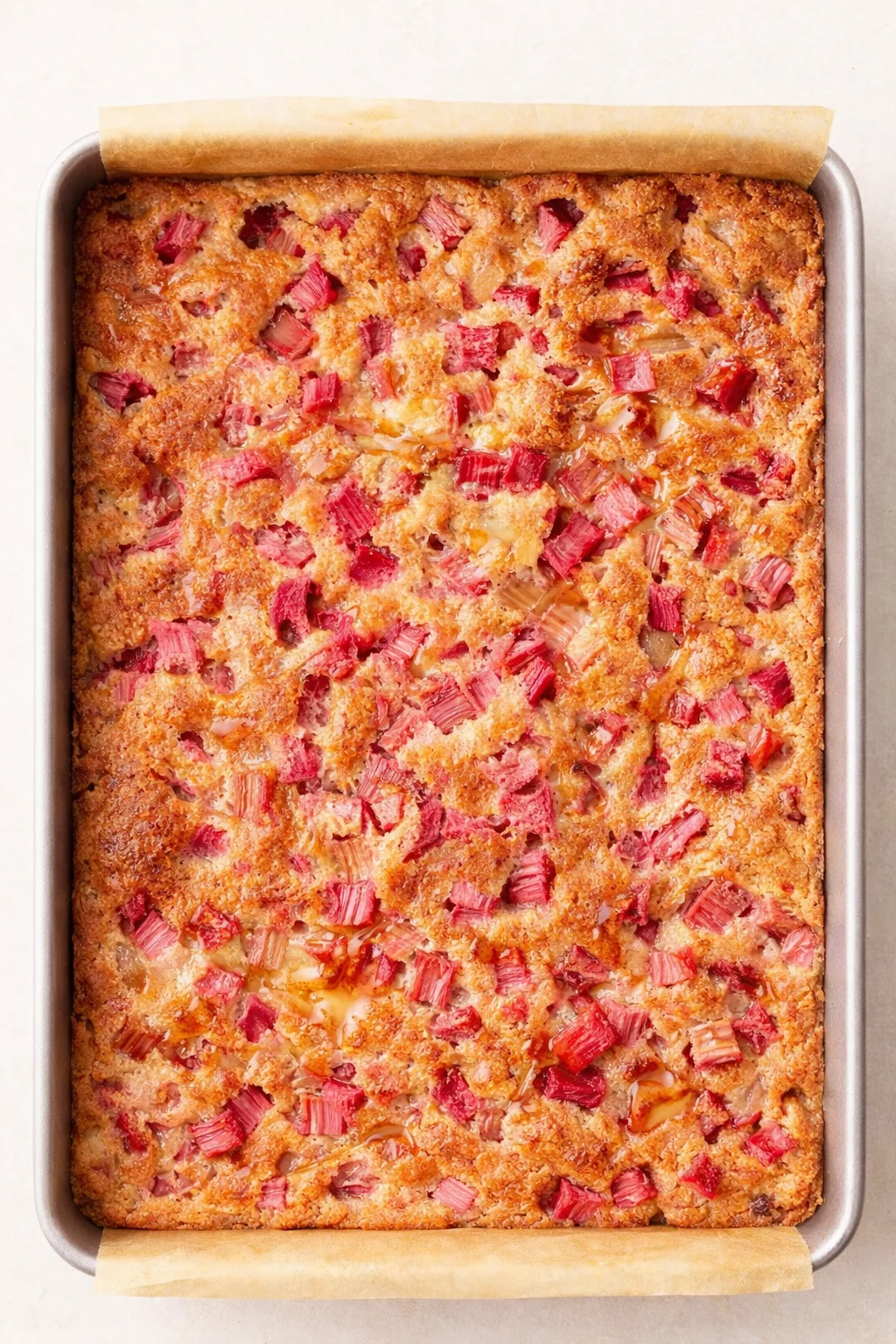 top-down view of a rhubarb crumble in a parchment-lined baking pan