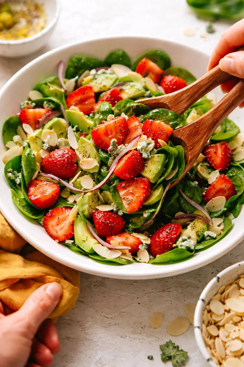 bowl of strawberry avocado salad with greens, onion, almonds, and blue cheese crumbles