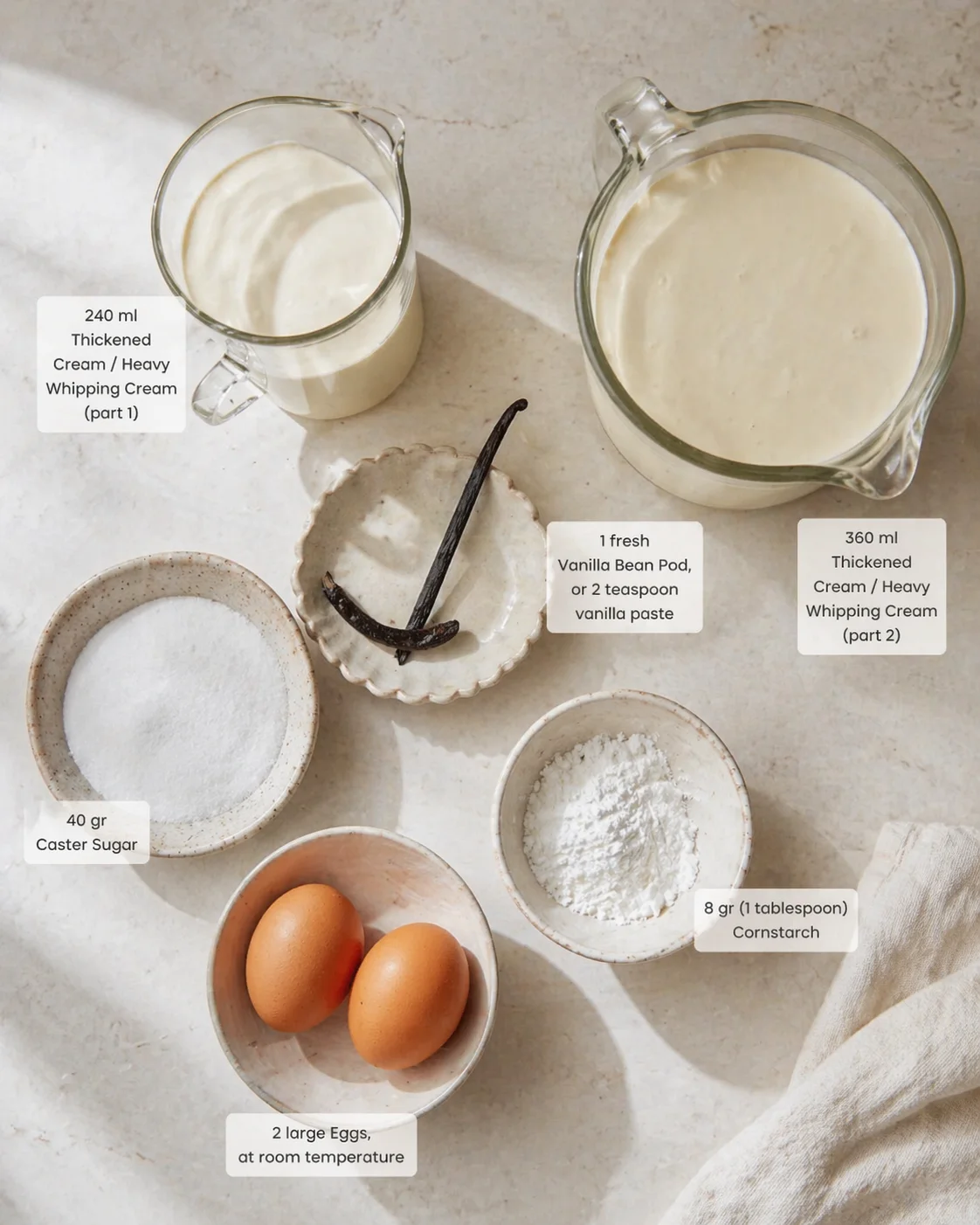 Flat lay of vanilla cream ingredients: eggs, sugar, cornstarch, vanilla bean, and cream in glass bowls.