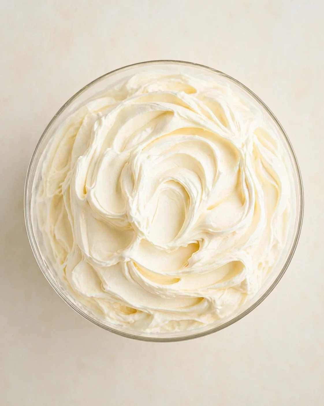 Top-down view of a glass bowl filled with swirled whipped cream.