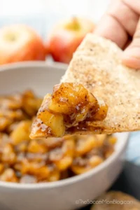 dipping a tortilla chip into apple salsa.