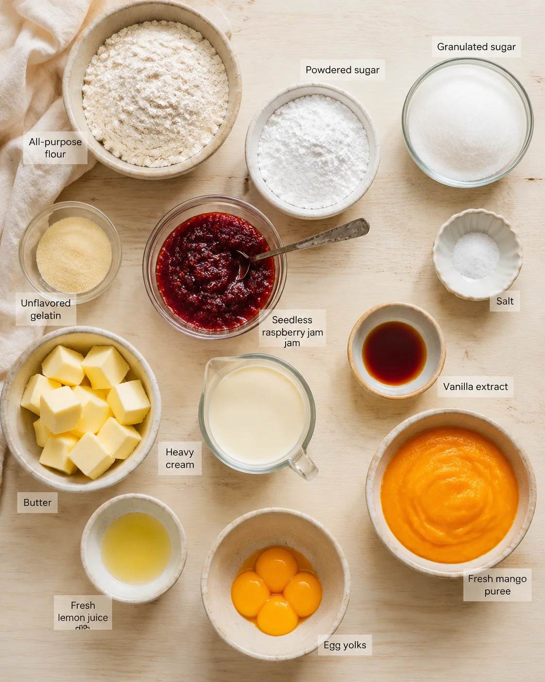 Overhead shot of labeled baking ingredients arranged on a light wooden surface.