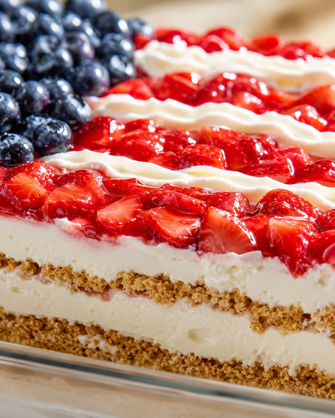close-up of a berry-topped cheesecake with blueberry cluster, whipped-cream ribbons, and crumb crust