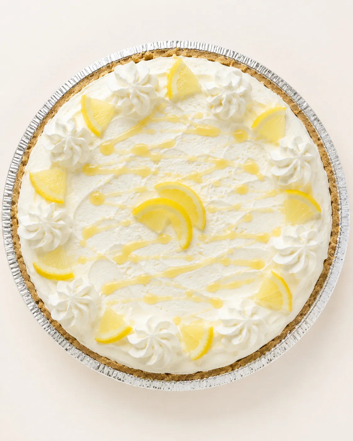 top-down view of lemon cheesecake pie with whipped cream rosettes and lemon wedges