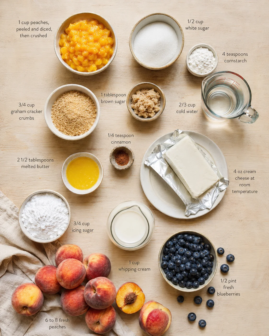 Overhead view of arranged baking ingredients with peaches, blueberries, cream cheese, and labeled measurements