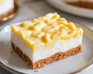 slice of cheesecake with crumb crust and lemon-curd topping on a white plate