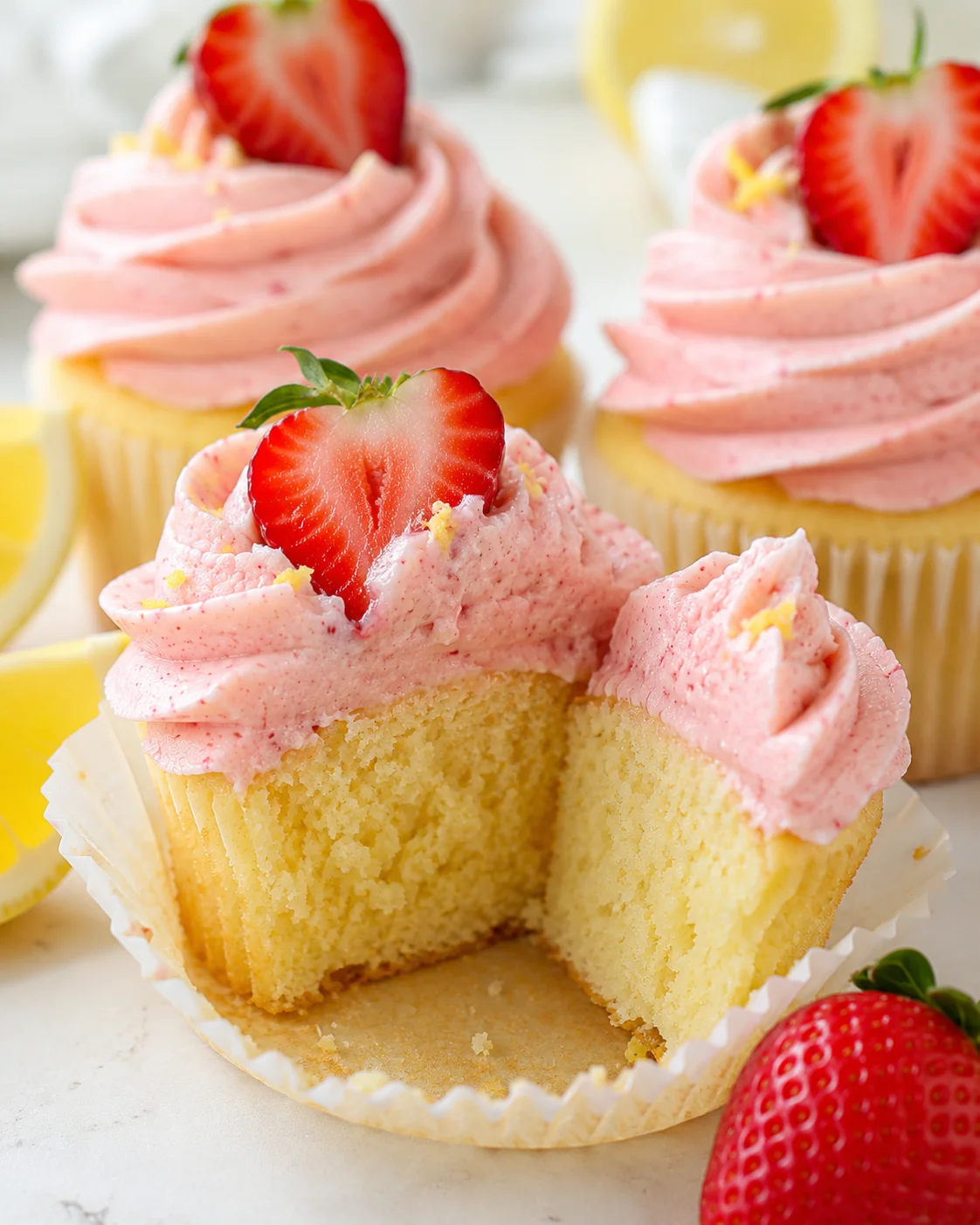 Close-up of strawberry lemonade cupcakes with pink frosting and fresh strawberries