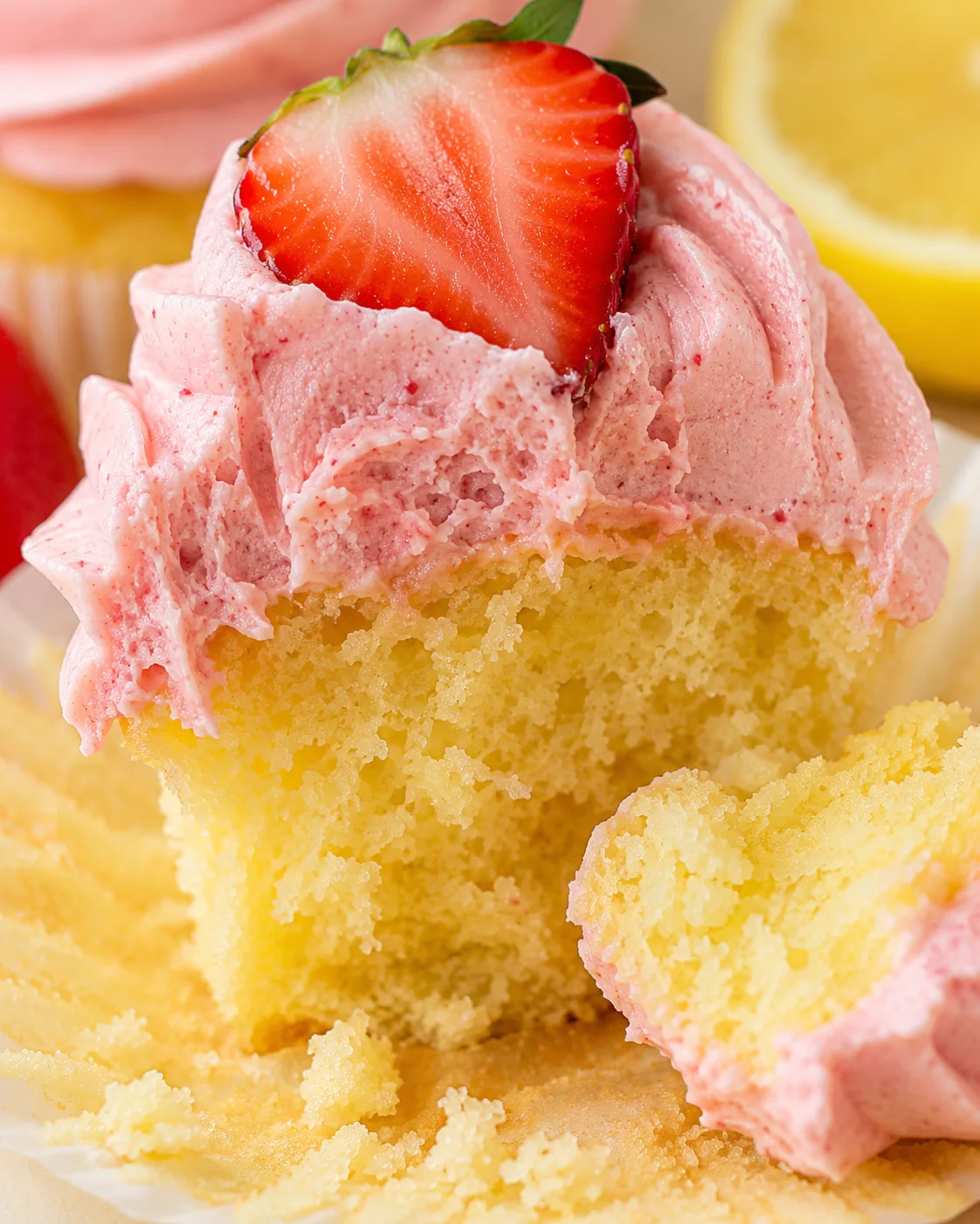 Close-up of a cupcake topped with strawberry frosting and half a strawberry garnish.