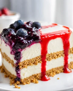 Close-up side view of sliced icebox cake showing graham layers, creamy filling and glossy berry drip.