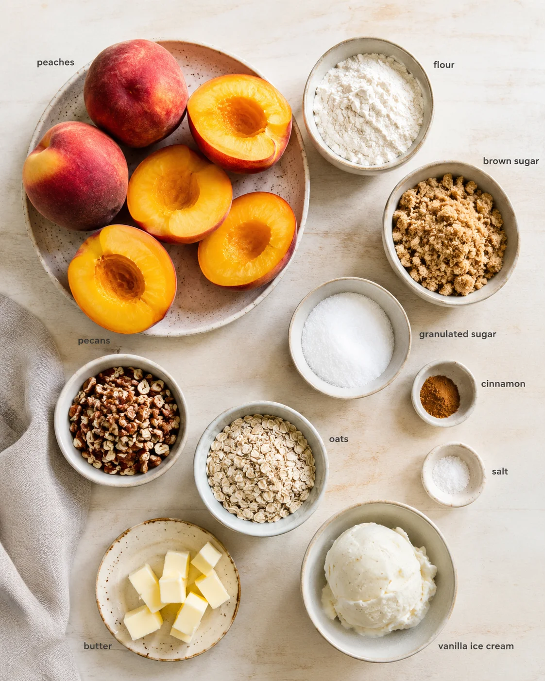 Overhead view of peaches and baking ingredients arranged on a pale wooden surface.