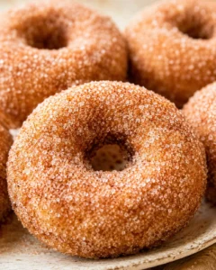 Close-up of freshly baked apple cider donuts coated in cinnamon sugar.