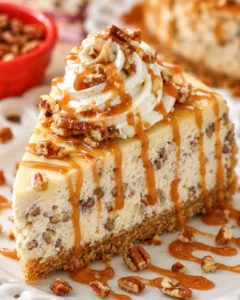 A slice of pecan cheesecake topped with whipped cream and caramel drizzle.