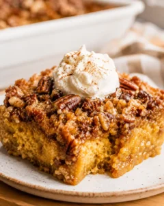 Close-up of pumpkin dump cake topped with whipped cream and pecans.