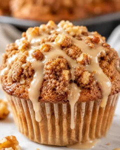 Close-up of a golden maple walnut muffin topped with glaze and streusel.