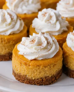 Close-up of mini pumpkin cheesecakes topped with whipped cream and cinnamon
