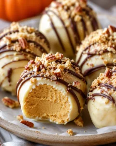 Close-up of creamy pumpkin cheesecake balls drizzled with chocolate and topped with nuts.