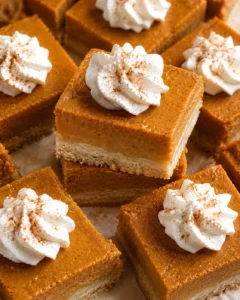 Close-up of pumpkin pie bars topped with whipped cream and cinnamon