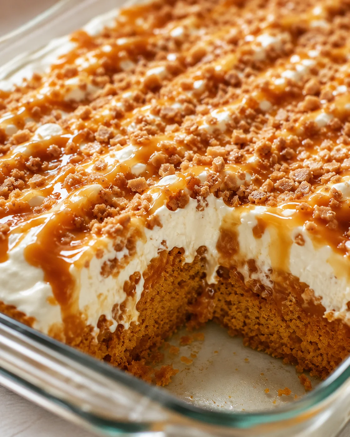 Delicious pumpkin cake topped with caramel drizzle, Cool Whip, and crunchy Heath bits.