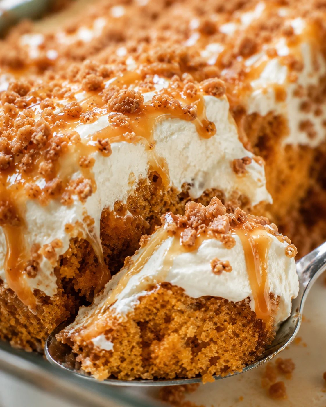 Close-up of a delicious pumpkin cake topped with whipped cream, caramel, and crunch bits.
