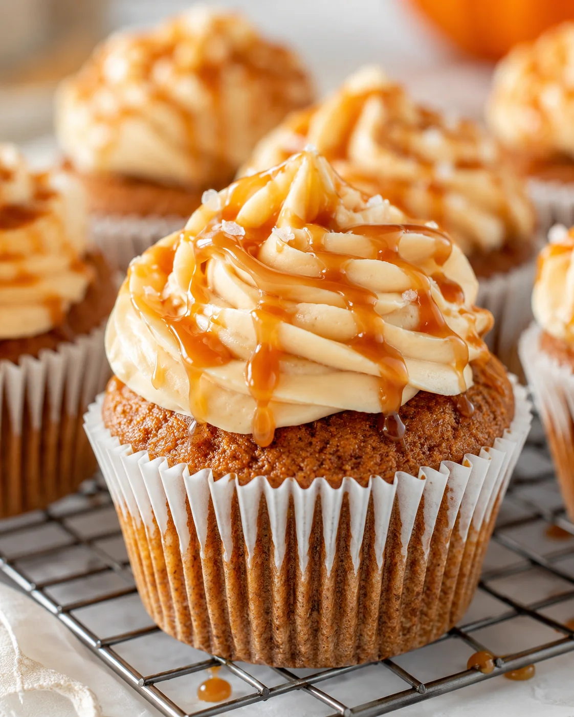 Close-up of pumpkin cupcakes topped with creamy caramel frosting and salted caramel drizzle